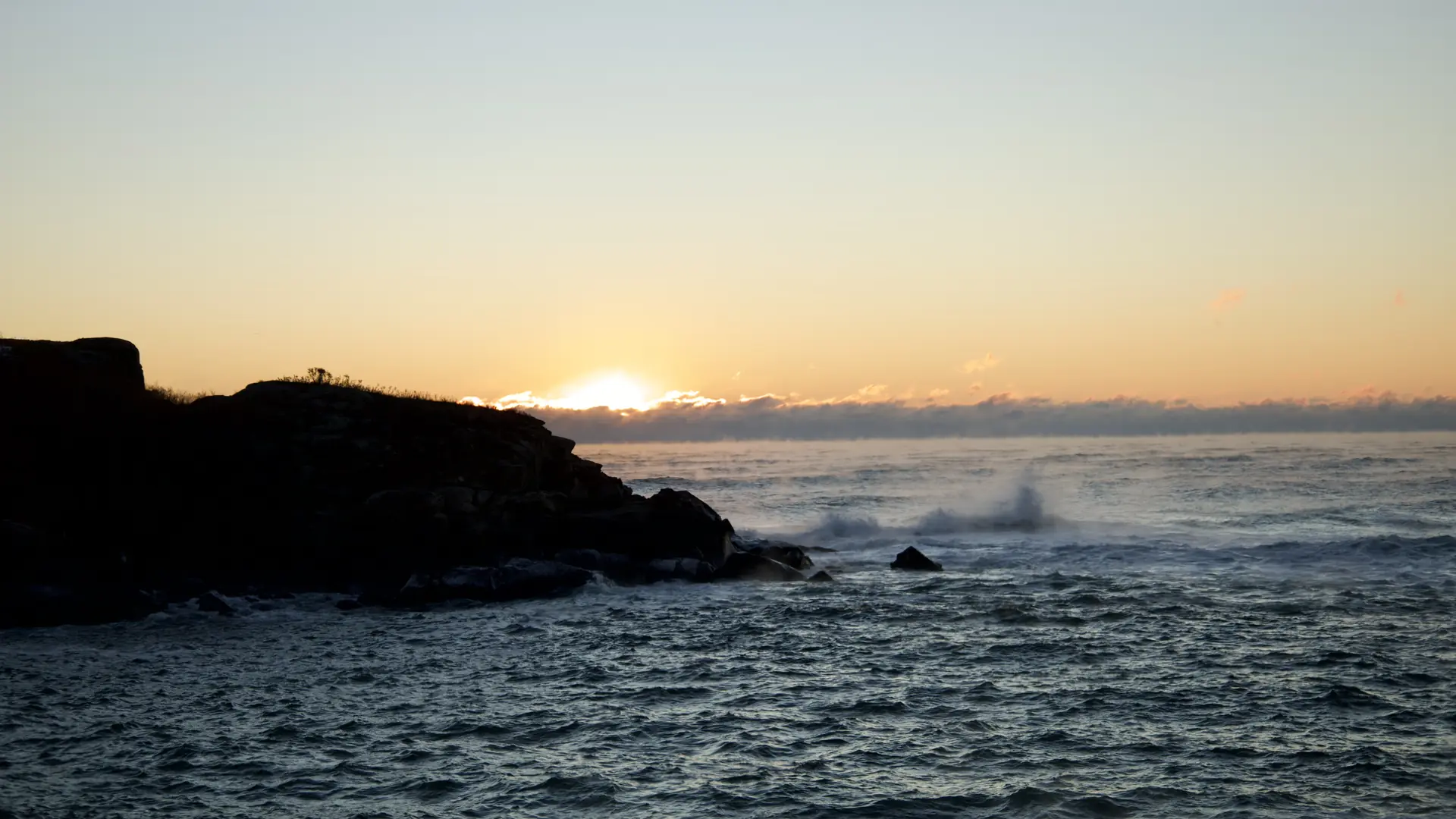 L’océan au lever du jour, un rocher sombre et les vagues, au bout de la rue