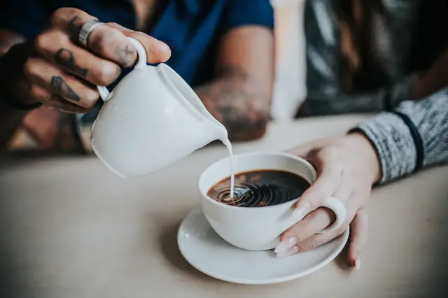 Un nuage de lait dans le café, à table — Agrandir