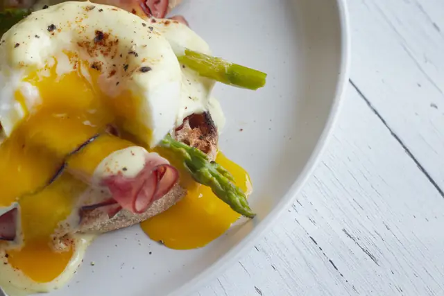 L’œuf Benedict ouvert, le jaune qui coule sur le jambon — Agrandir