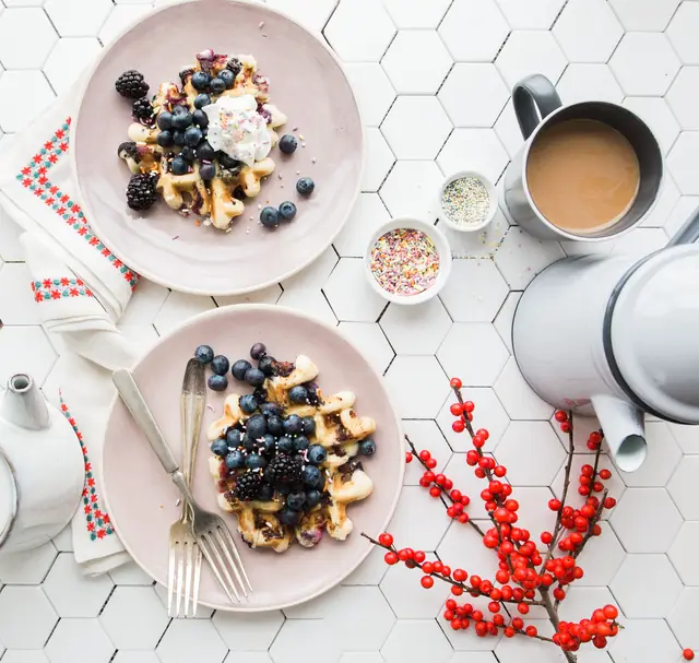 Deux gaufres aux myrtilles et à la crème, le café à côté — Agrandir