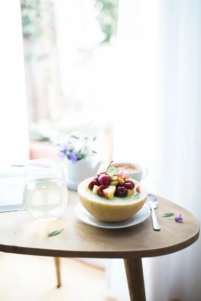 Un demi-melon garni de fruits, sur le guéridon du salon — Agrandir